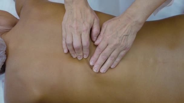 Tangan wanita memijat punggung seorang wanita muda. Konsepsi perawatan tubuh. Top view — Stok Video