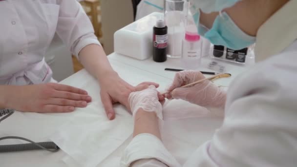 Chelyabinsk. Rusia. dec 12. 2020. un maestro del cuidado corporal spa en una túnica blanca y máscara hace una manicura en otra mano de las niñas, primer plano en movimiento, solo las manos sin rostro son visibles — Vídeos de Stock