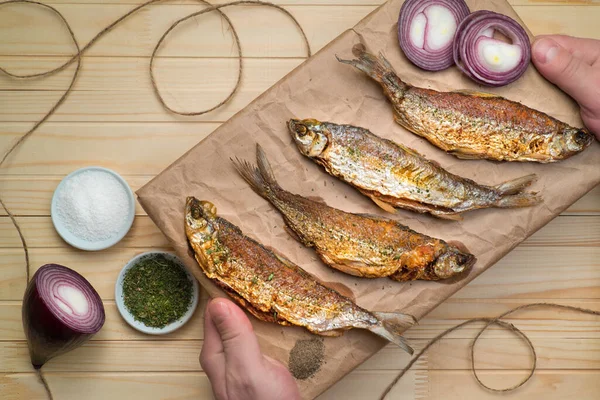 Lezzetli kızarmış küçük balıklar, el sanatları kağıdının üstünde yukarıdan ahşap masa manzaralı.