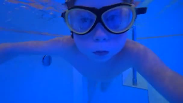 Kind mit Schwimmbrille schwimmt im Winter in einem Becken in einer Thermalquelle im Freien — Stockvideo