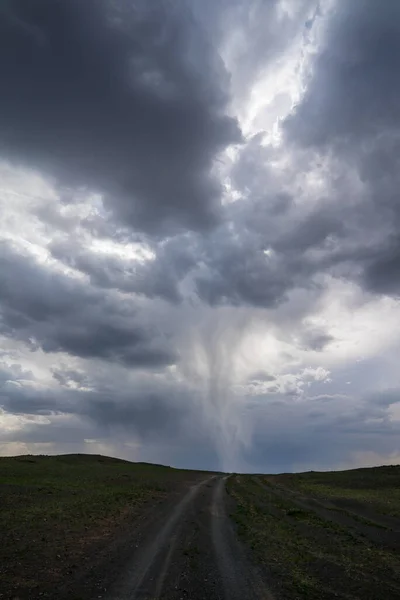 Moğolistan 'da toprak bir yol üzerinde fırtınalı bir gökyüzünde kasırga, dikey yerleşim