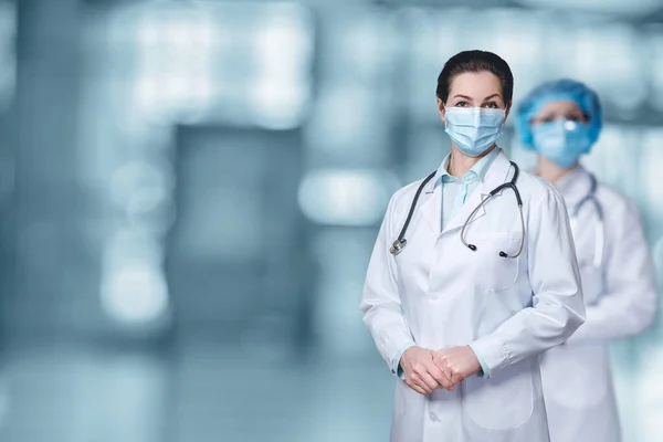Medical care concept. Doctors in masks stand on a blurred background.