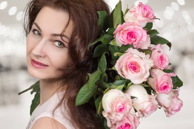 Bulanık arka planda gül buketi olan bir kadın..