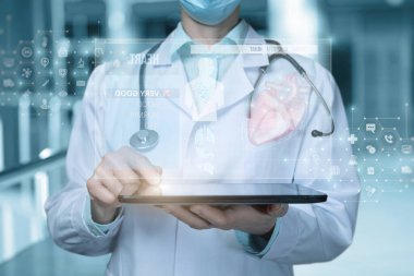Doktor sanal ekranlı bir tablet üzerinde çalışıyor. Hastanın kalbini inceliyor..