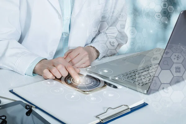 Doctor working on mobile devices ah and computer on blurred background.