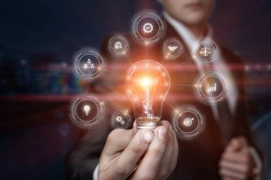 Yenilikçi entegre iş fikri. İş adamı iş simgelerinin arka planında yanan bir ampul gösteriyor.