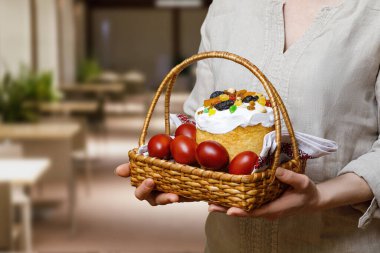 Kadın paskalya pastası ve bulanık arka planda boyanmış yumurtalar gösteriyor..