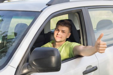 Araba süren genç bir adam el sallıyor..