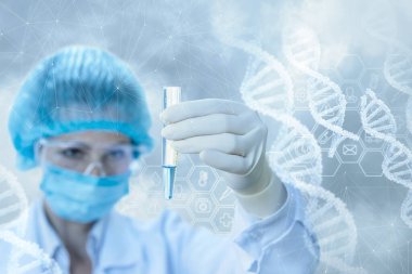 Laboratuvar temsilcisi, arka planda ve DNA örneğinin bulunduğu bir test tüpüne bakıyor..