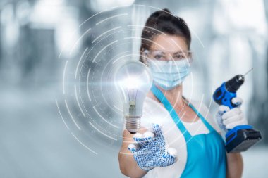 Yenilemedeki kavramsal fikirler kavramı. İşçi elinde matkapla yanan bir ampulü tıklatır..