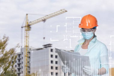 İnşaat alanının arka planında projeye bakan kadın inşaat mühendisi.