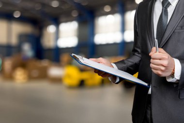 İşadamı depoyu teftiş ediyor. Bir işadamı depo ortamında envanter ve notları kontrol eder..