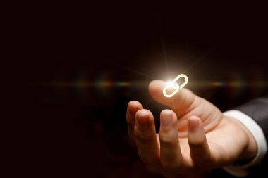 Fikirleri amaca bağlamak. Bir el, yaratıcılıktaki birliği ve bağlantıyı sembolize eden parlak bir zincir halkası tutar..