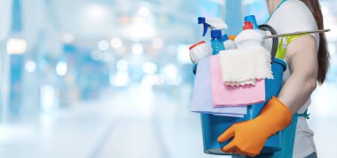 Bir insan bir kova dolusu temizlik aletini parlak ve modern bir ortamda tutar..