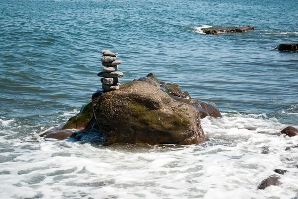 Torre de seixo empilhada sendo lavada por Onda — Fotografia de Stock