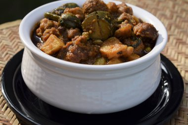 Hint Gujarati Özel Yemek Türü Undhiyu veya Undhiya yakın plan sarı arka plan, tavus kuşu tüyleriyle süslenmiş. Ahmedbad Gujarat 'taki uttaray festivali sırasında ev yemeği.