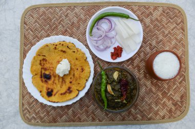 IndiaMakki roti and sarson saag with onion chilly salad and earthened glass of sweet lassi in an authentic way with white butter and green chilly. Punjabi traditional style food clipart
