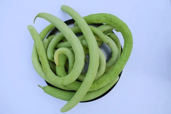 Yard-long snake cucumbers heap, very long thin curvy light green cucumber bunch on white background.