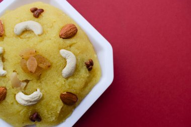 Geleneksel Hint tatlıları irmik ya da Rawa 'dan yapılmış Kesari banyosu olarak bilinen fındıkla süslenmiş. Kırmızı arka planda Güney Asya tatlısı. Selamlama için yazı tipi yazmak için boş alan