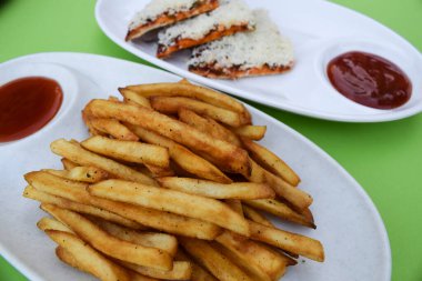 Elinde çıtır çıtır patates kızartması tutan bir kadın. Baharatlı masala soslu patates cipsi. Dünya çapında yenen çok lezzetli bir çay saati atıştırmalığı. Patates kızartması dışarıda servis ediliyor.