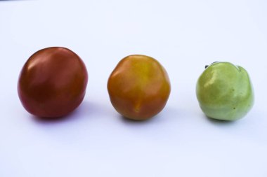Domatesin üç renk ya da renginin seçici odağı gençlikten olgunluğa ya da olgunlaşmamış domateslere beyaz arka planda renkli.