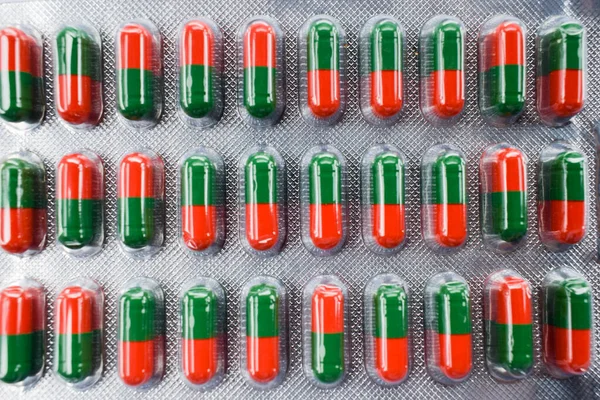 赤と緑の色でカプセル背景 副鼻腔症状軽減のためのアーユルヴェーダの錠剤のテクスチャ — ストック写真