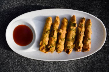 Beyaz tabakta domates ketçaplı çıtır mısır böreği. Lezzetli kızartılmış bebek mısırlı Pakoda atıştırmalıkları.