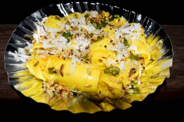 Khandvi a traditional and authentic Gujarati dish item eaten served as savoury snacks. tempered and garnished with grated coconut, green chilly, sesame seeds