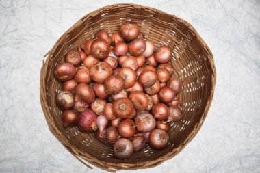 Hindistan ve Pakistan 'da yuvarlak kahverengi hasır bambu sepetinde depolanmış küçük soğanların üst görüntüsü..