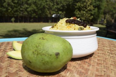 Ugadi festivali yemeği Mango pilavı aynı zamanda mamidikaya pulihora olarak da bilinir. Bu geleneksel pirinç tarifi yeni yıl kutlamaları sırasında hazırlanmıştır. Hasır arka planda servis edilir