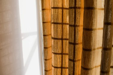 Yarı şeffaf, ince kumaşlı, kare desenli perdeler. Sabah güneşi Hint evlerinin iç kısımlarını perdeliyor.