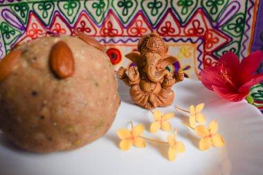 Güzel Lord Ganesha evde oturan sevimli putperest Pooja duası işlemeli motif çok renkli dekorasyon arka planına sahip. Prasad of buğday atta laddu ile sunuldu