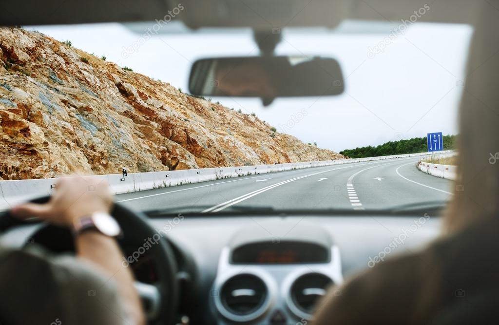 Driver's hands on steering wheel inside of a car