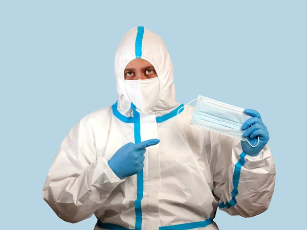 A doctor in a protective suit holds a medical mask in his hand during the Covid pandemic