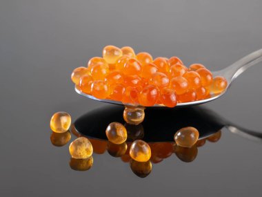 Kırmızı havyar kaşıkta yakın plan. Sağlıklı yiyecekler. Karanlık bir arka planda yansıması olan somon yumurtası. Deniz ürünleri lezzetleri, omega