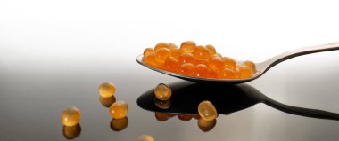 Kırmızı havyar kaşıkta yakın plan. Sağlıklı yiyecekler. Karanlık bir arka planda yansıması olan somon yumurtası. Deniz ürünleri lezzetleri, omega