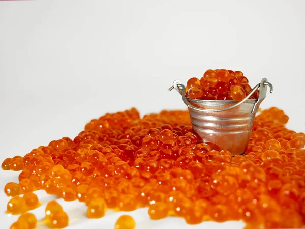 Huevas de salmón rojo en un pequeño cubo sobre un fondo claro. Buena comida, delicadeza, mariscos. La textura del caviar. — Foto de Stock