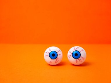 Cadılar Bayramı için turuncu arka planda korkunç ve komik gözler, kopyalama alanı