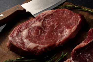 Tahta kesme tahtasının üzerinde çiğ mermer biftek.