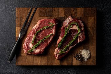 Tahta kesme tahtasının üzerinde çiğ mermer biftek.
