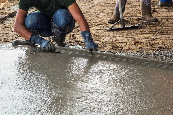 Mand murer opbygge et støbt gulv frakke cement på gulvet - Stock-foto