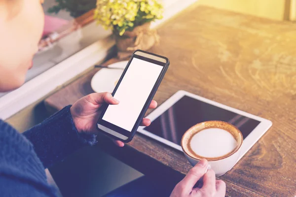 Frau spielt Smartphone und trinkt Kaffee mit Vintage-Ton. — Stockfoto