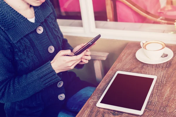 Mano donna utilizzando smartphone in caffetteria e luce morbida — Foto Stock