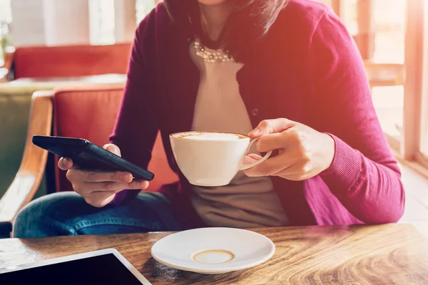 Hand kvinna med telefon och cup i kafé — Stockfoto