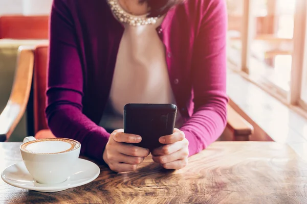 Donna che utilizza il telefono cellulare nel caffè. Femmina seduta in caffè e tazza — Foto Stock