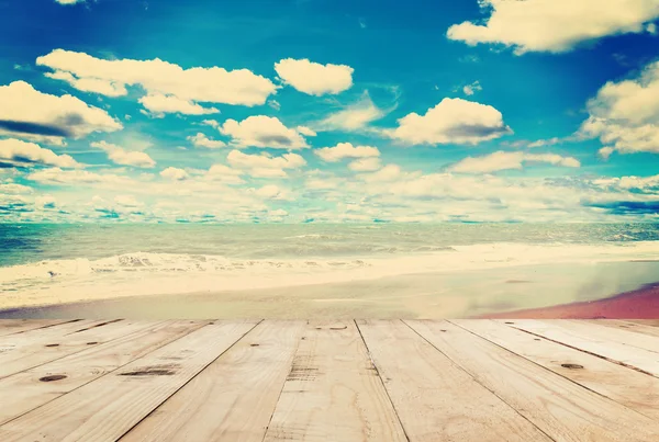 Trä table sand beach havet och himlen molnen med vintage ton. — Stockfoto