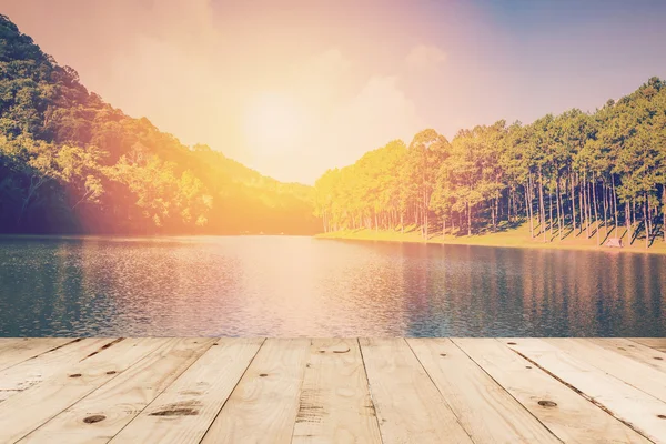 Bord av trä och damm vatten och soluppgång med vintage effekt. — Stockfoto