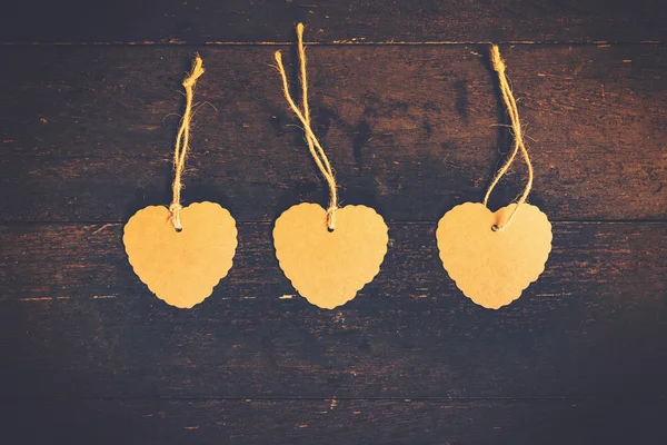 Blank brown tag heart shape on old wood background with space. — Stock Photo, Image