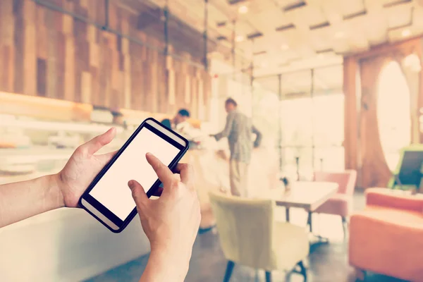 Hånd med smarttelefon og utydelige personer i kaffebar med vin – stockfoto