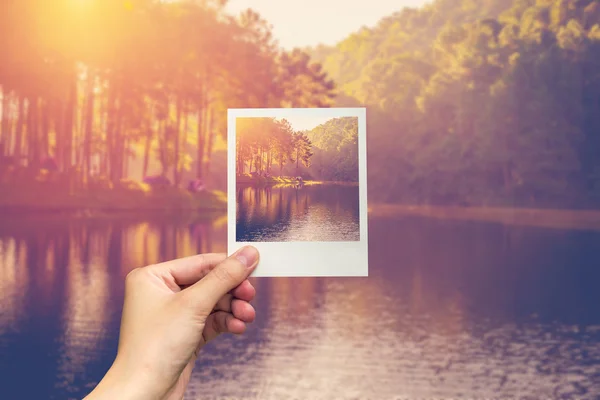 Hand halten Instant-Foto Teichwasser und Sonnenaufgang mit Vintage-Effekt. — Stockfoto